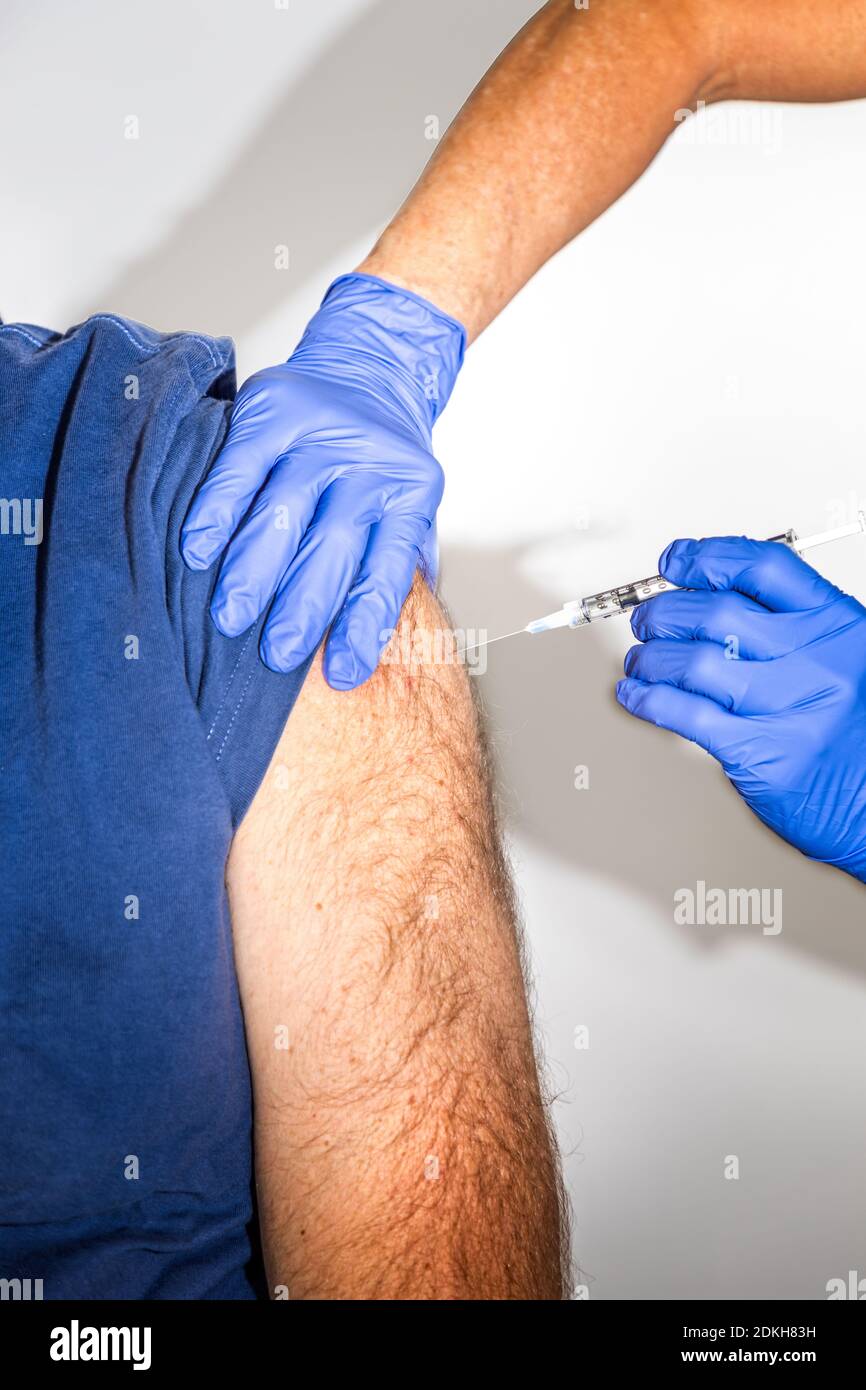 L'uomo adulto caucasico riceve la vaccinazione Covid-19 da un operatore sanitario Foto Stock