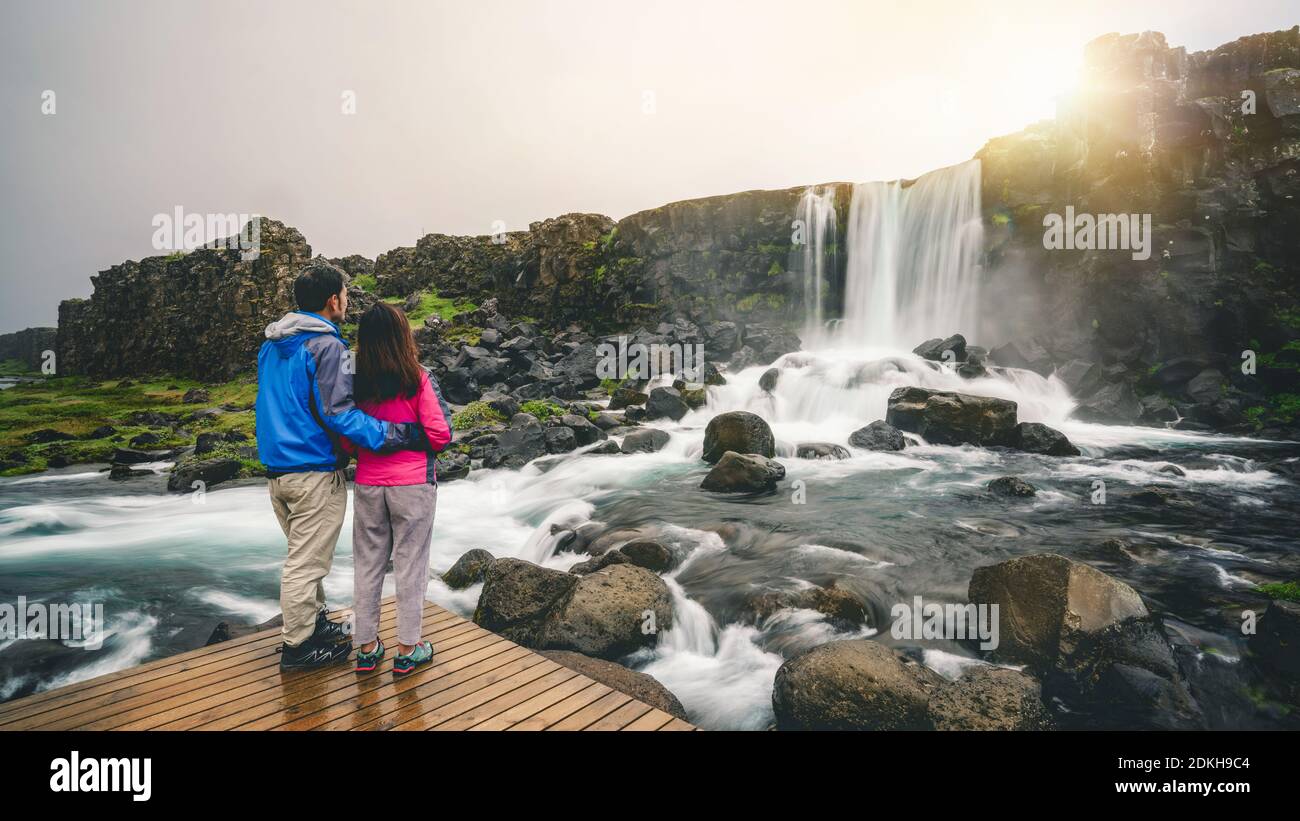 Accoppiare i viaggiatori viaggiare a cascata Oxararfoss a Thingvellir National Park, Islanda. Cascata Oxararfoss è famosa cascata attira turisti per Foto Stock