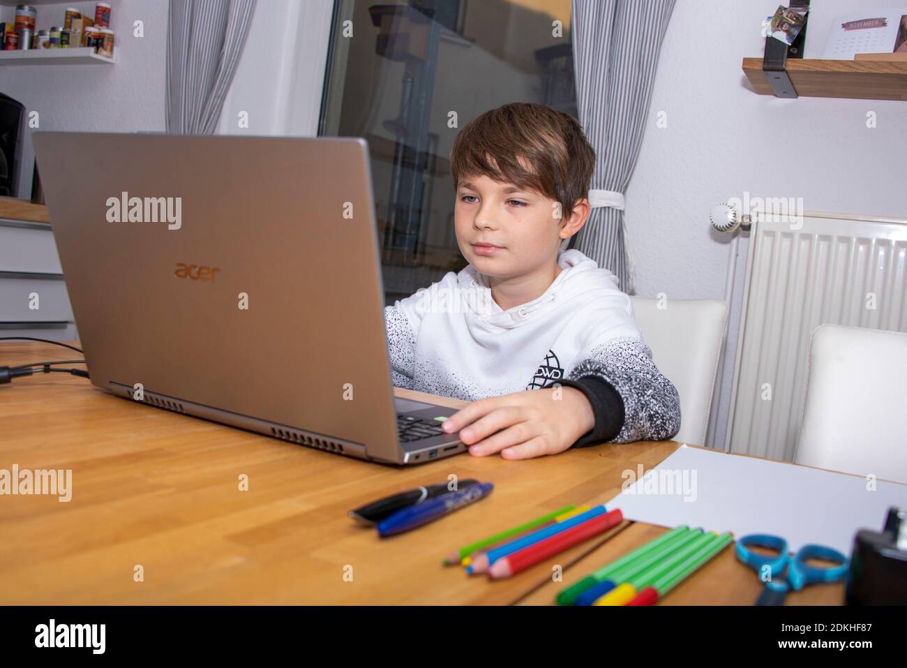 Ragazzo seduto di fronte a un computer portatile in casa Foto Stock