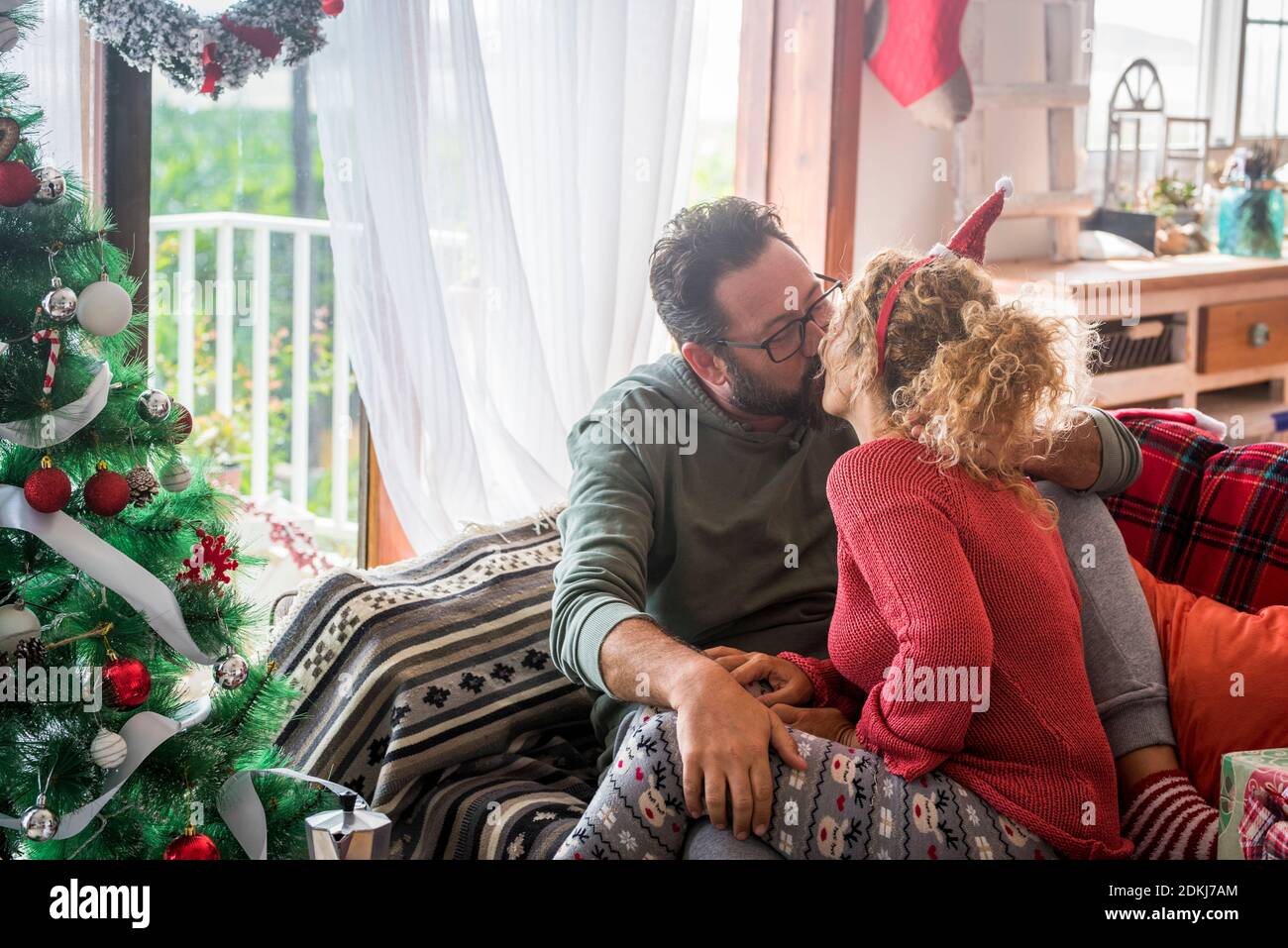 Coppia adulta persone caucasiche in amore baciare e condividere la dolcezza a casa durante le vacanze invernali di natale - concetto di celebrazione e la vita insieme per sempre con felice uomo e donna bacio l'uno con l'altro Foto Stock