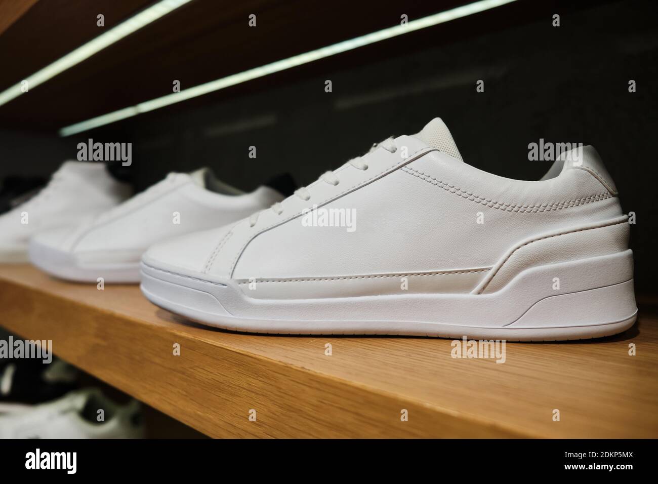 Sneaker casual bianche bianche bianche sullo scaffale del negozio di calzature Foto Stock