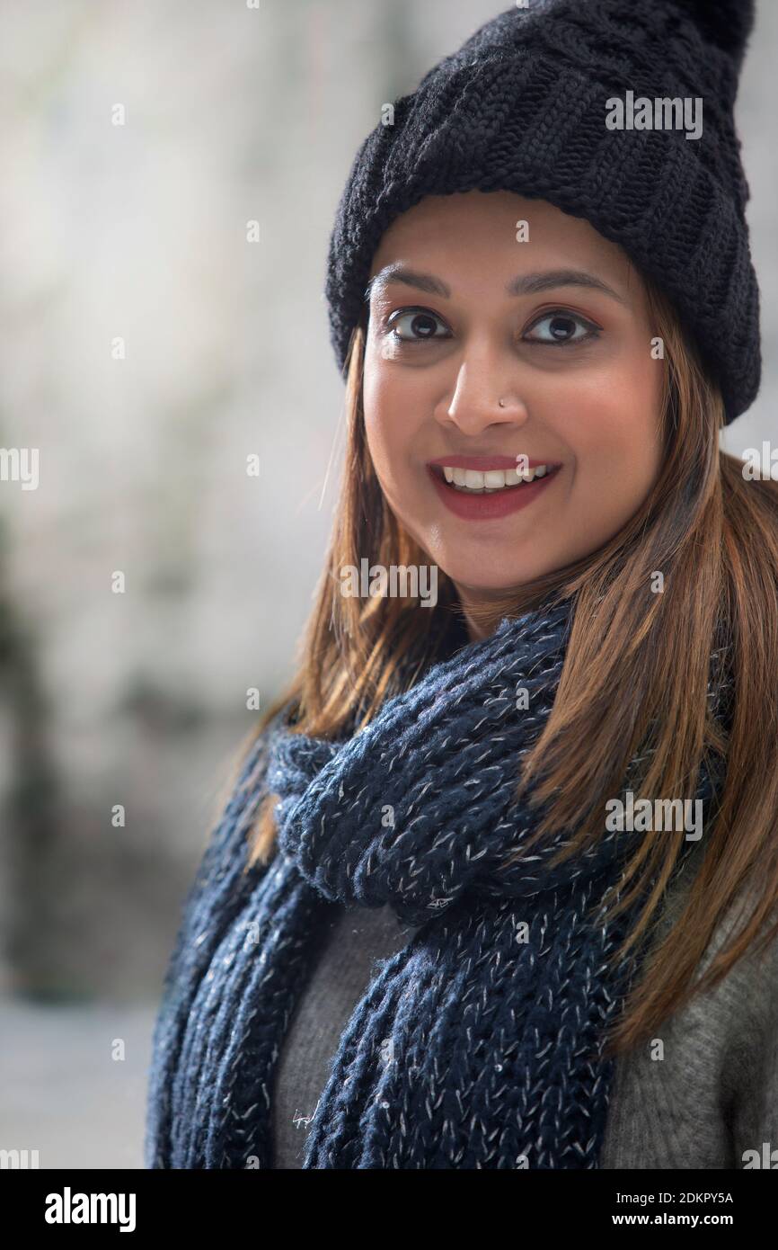 RITRATTO DI UNA GIOVANE DONNA IN ABITI DI LANA GUARDANDO FOTOCAMERA E SORRIDENTE Foto Stock