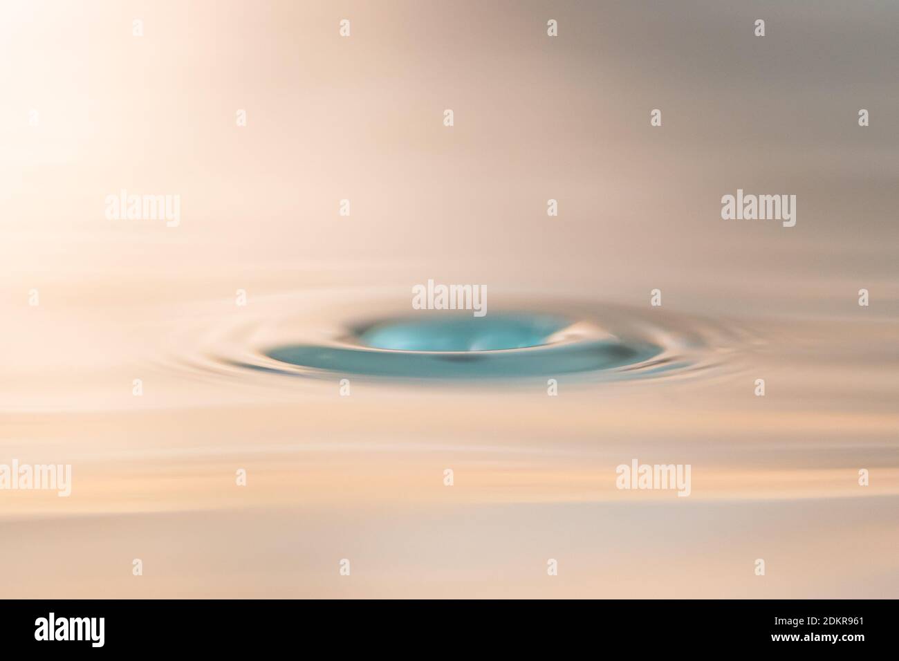 Primo piano foto di una goccia d'acqua che colpisce la superficie dell'acqua e crea una cavità. Questa foto può essere utilizzata per tutti i tipi di scopi. Foto Stock