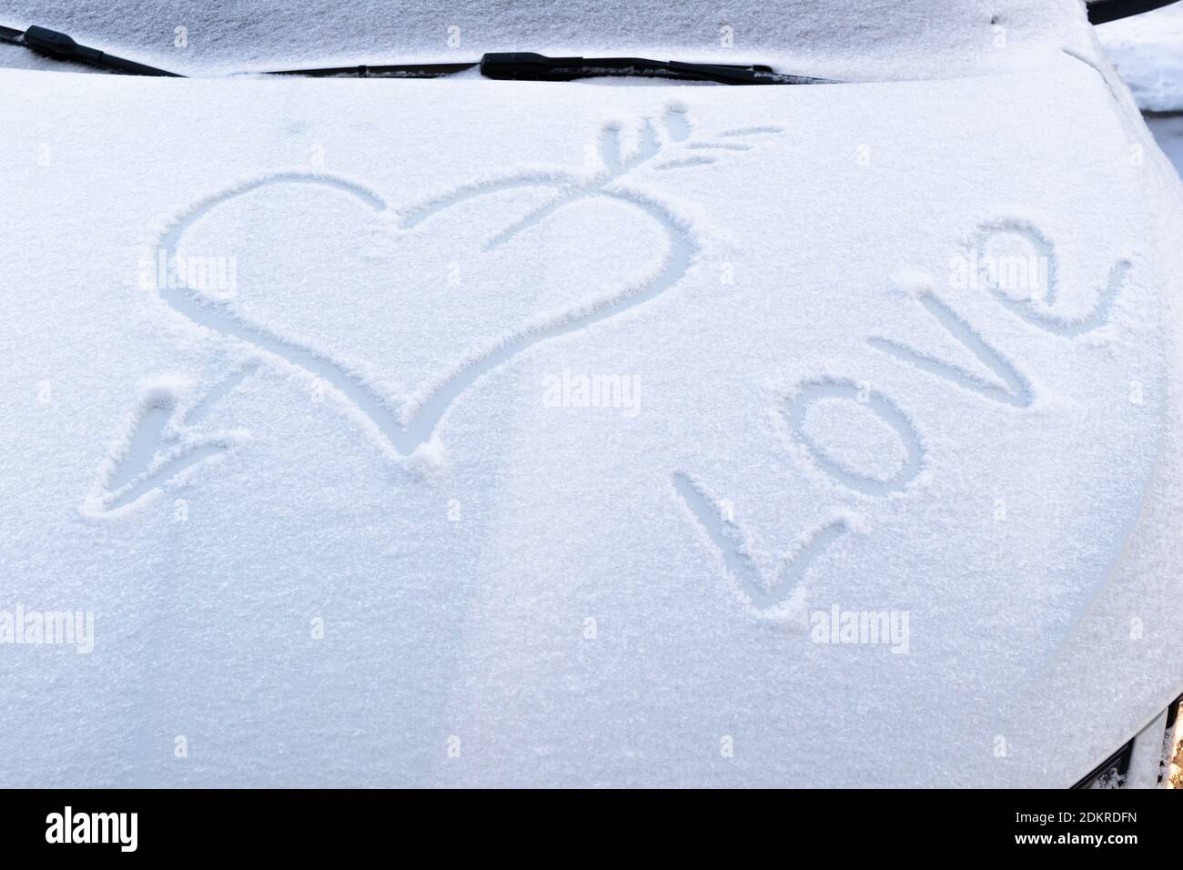 immagine di un cuore rotto con una freccia nel neve sul cofano di un'auto su una gelata giorno invernale Foto Stock
