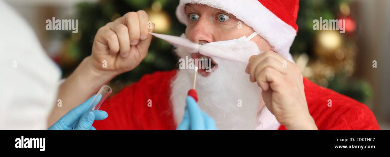 Medico in tuta protettiva che prende PCR striscio da babbo natale Vicino albero di Natale Foto Stock