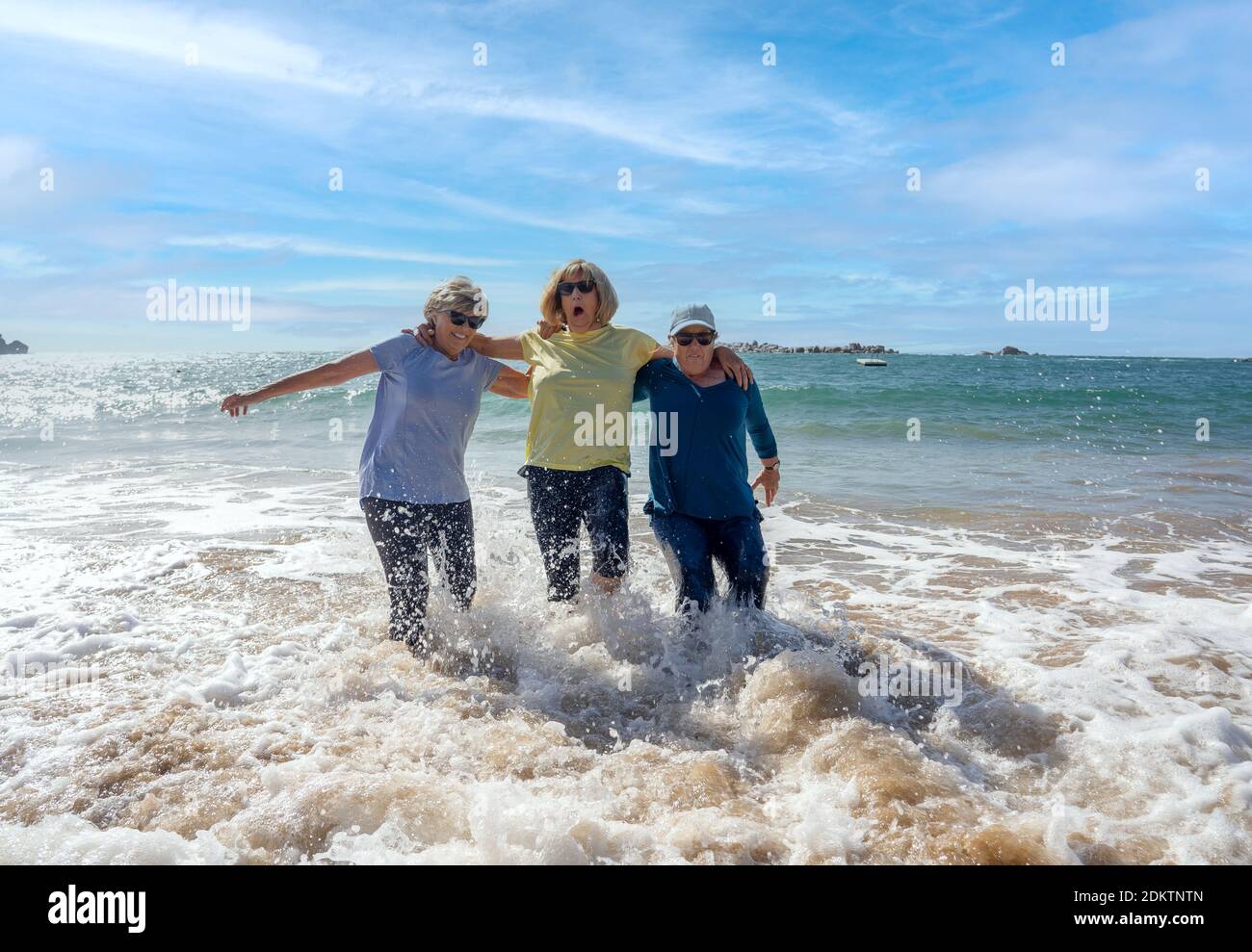 Gruppo di donne anziane in pensione sui loro anni '60 e '70 cadendo in acqua divertirsi sulla spiaggia. Le Signore più anziane ridono mentre cadono giù perdendo balan Foto Stock