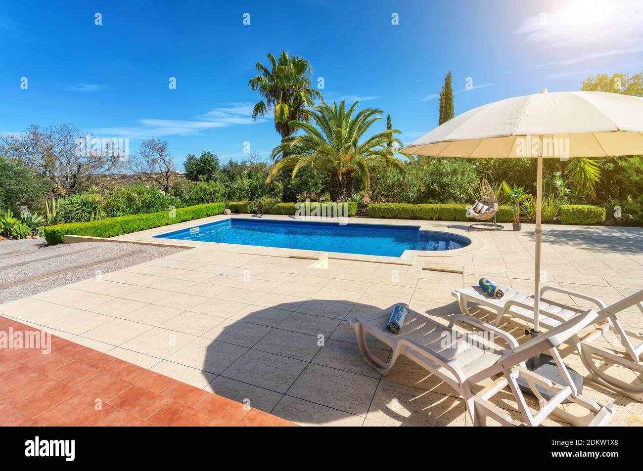 Piscina di lusso nel giardino di una villa privata, sedia pensile con cuscini per turisti, in estate. Portogallo, Algarve. Foto Stock