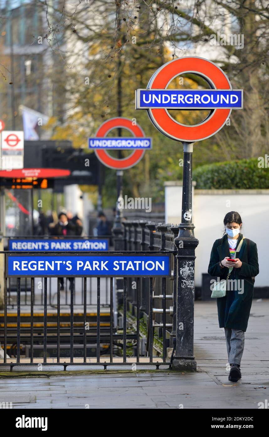 Londra, Inghilterra, Regno Unito. Ingresso alla stazione della metropolitana Regent's Park su Marylebone Road. Giovane donna sul suo telefono e indossare una maschera facciale durante il COVID Foto Stock