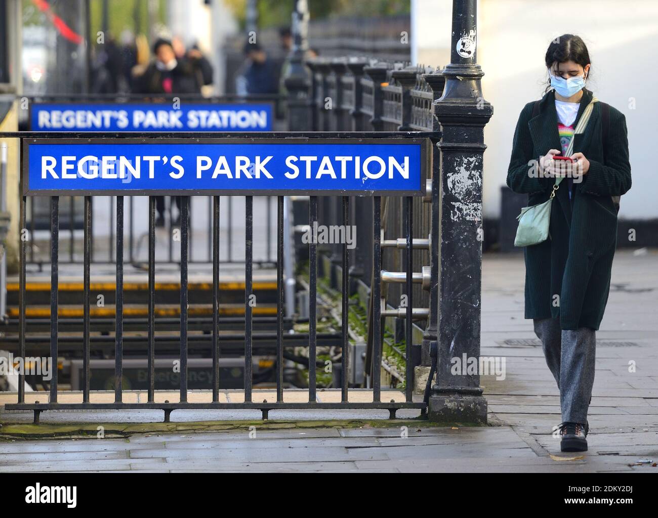 Londra, Inghilterra, Regno Unito. Ingresso alla stazione della metropolitana Regent's Park su Marylebone Road. Giovane donna sul suo telefono e indossare una maschera facciale durante il COVID Foto Stock