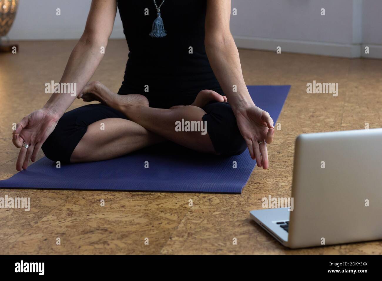 Allenatore femminile anonimo che utilizza un computer portatile per sessioni di allenamento digitale a casa. Donna che insegna lotus posa in classe online. Cosciente della salute, meditazione Foto Stock