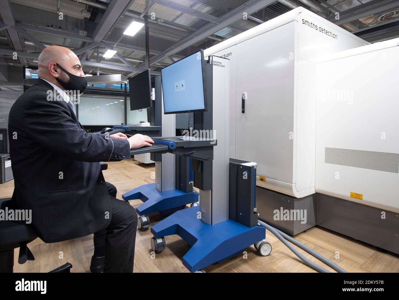 14 dicembre 2020, Hessen, Francoforte sul meno: Un addetto alla sicurezza  simula la funzione di uno scanner TC per bagagli nella gestione dei  passeggeri all'aeroporto di Francoforte. Si suppone che i dispositivi