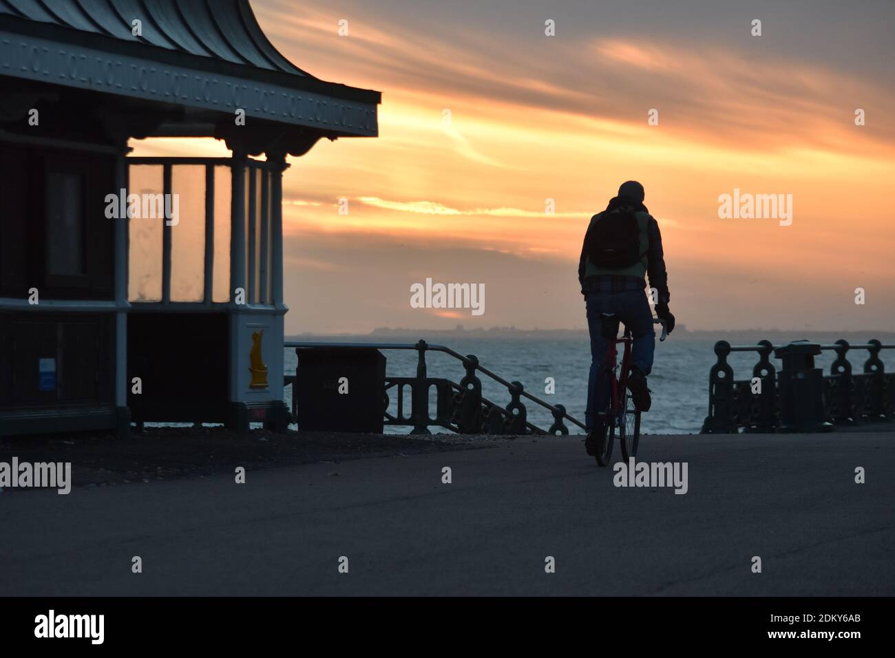 Ciclista sul lungomare al tramonto a Hove vicino Brighton, Sussex, Inghilterra, Regno Unito Foto Stock