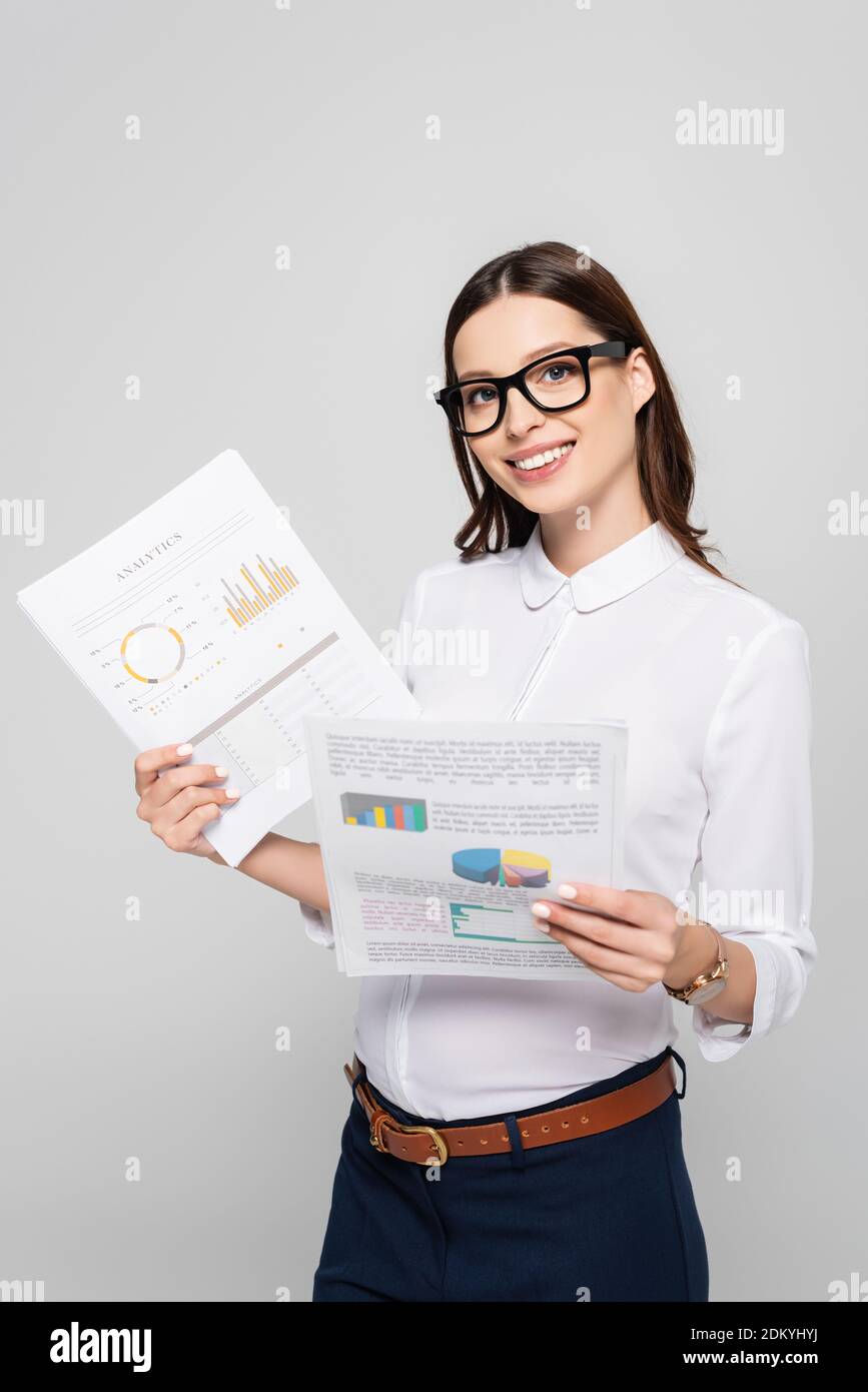 sorridente giovane donna d'affari incinta in occhiali che tengono le carte isolato sopra grigio Foto Stock