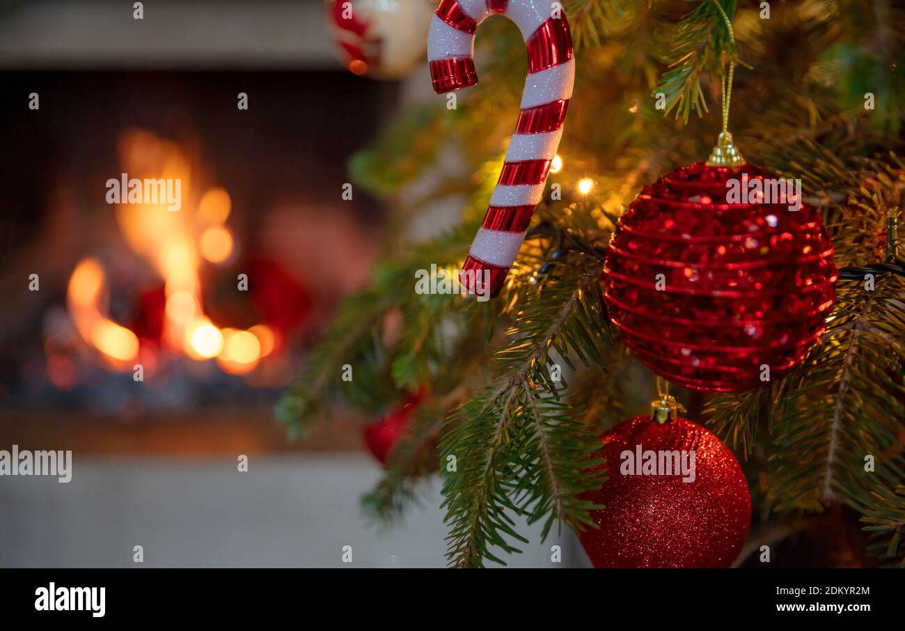 Albero di Natale, camino bruciante sfondo. Accogliente casa vacanze di Natale. Closeup bauble di Natale, biglietto d'auguri modello Foto Stock