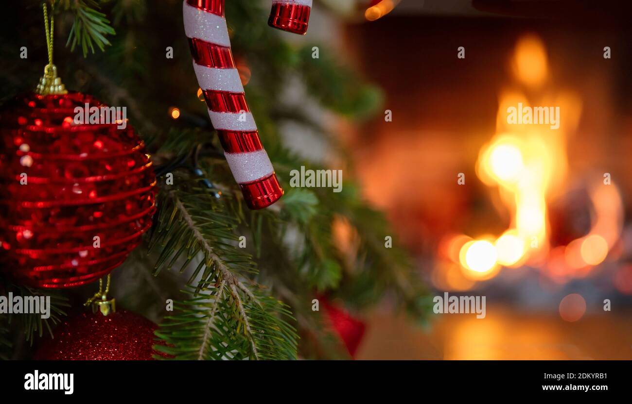 Albero di Natale, camino bruciante sfondo. Accogliente casa vacanze di Natale. Closeup bauble di Natale, biglietto d'auguri modello Foto Stock