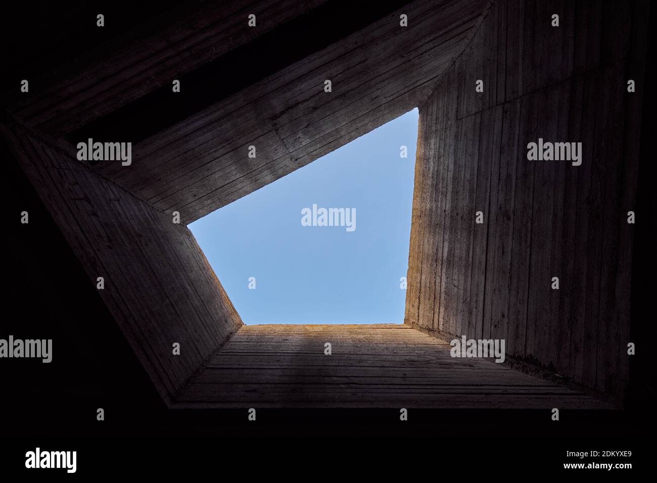 Imponente edificio in cemento che si affaccia sul cielo blu. Architettura geometrica astratta e contemporanea. Porta la luce alla prigione. Foto concettuale. Foto Stock