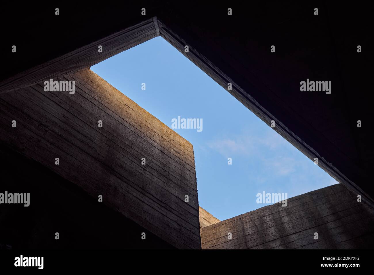 Imponente edificio in cemento che si affaccia sul cielo blu. Architettura geometrica astratta e contemporanea. Porta la luce alla prigione. Foto concettuale. Foto Stock