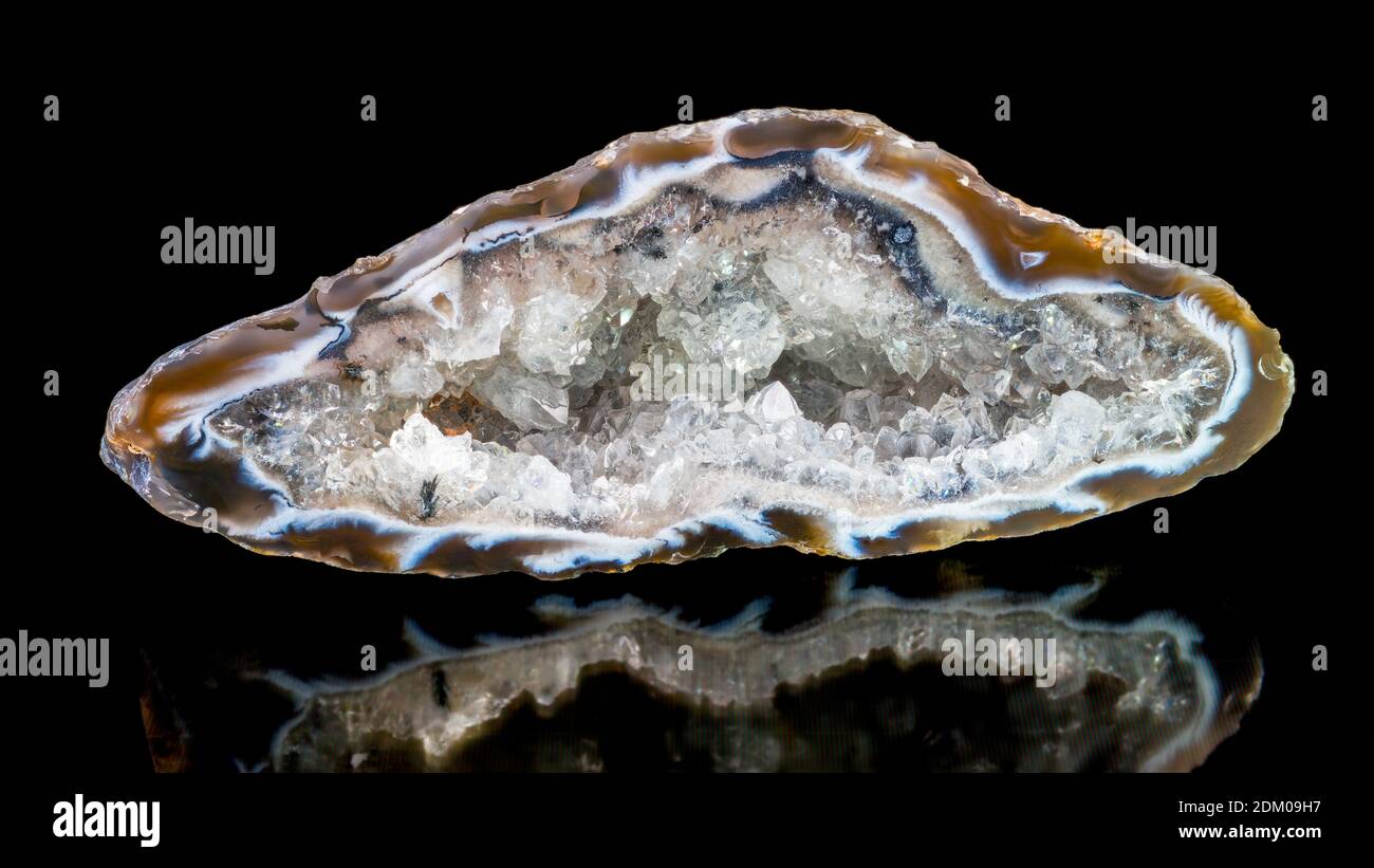 Cristallo di quarzo all'interno di un grande geode. Sezione gemma Agate con riflesso su sfondo nero. Minerale cristallino limpido in pietra preziosa tagliata cava. Foto Stock