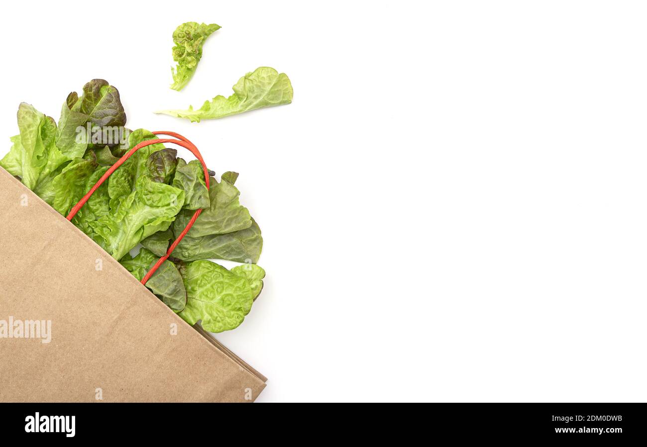 Sacchetto di carta con foglie di insalata verde, lattuga su sfondo bianco, layout con spazio per il testo Foto Stock
