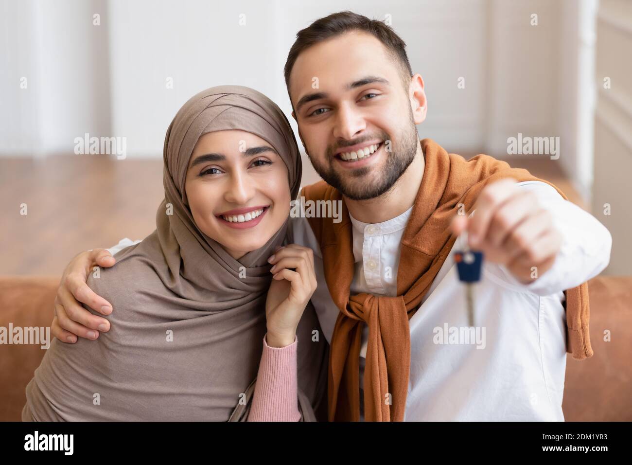 Allegra Famiglia musulmana giovane mostrando New House Key seduta al chiuso Foto Stock