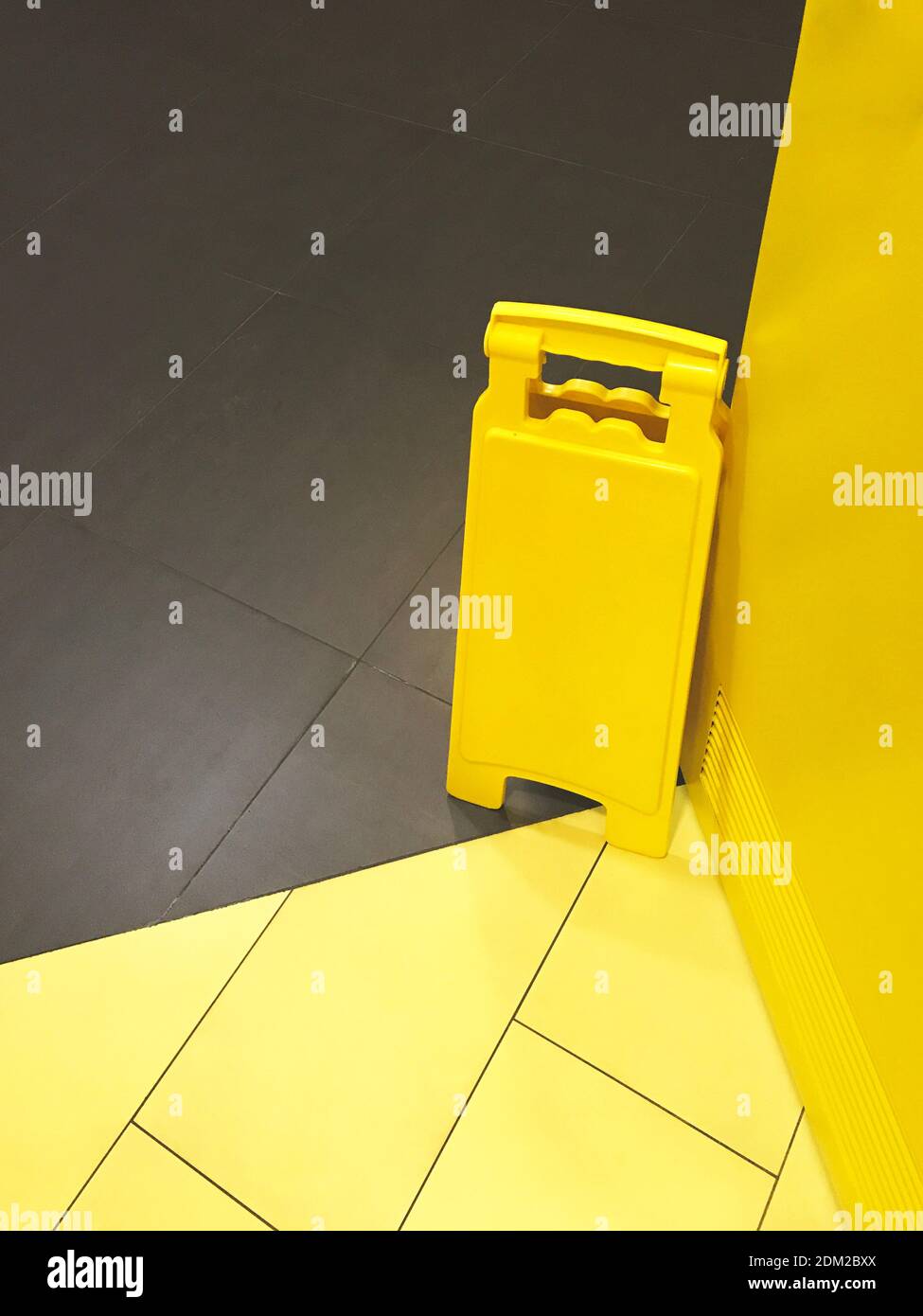 Cartello di avvertimento giallo sul pavimento grigio. 2021 colori dell'anno. Spazio vuoto per testo o disegno Foto Stock