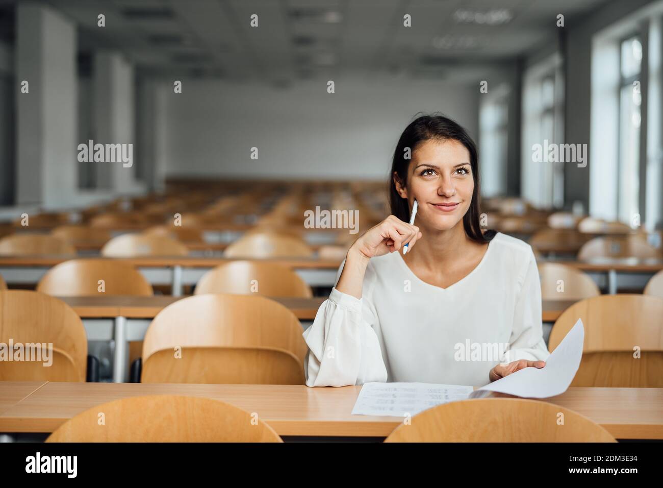 Una studentessa ben informata che partecipa a un esame facile in un anfiteatro vuoto. Uno studente ottimista che ha fatto un test in classe. Donna felice che ha stress fre Foto Stock