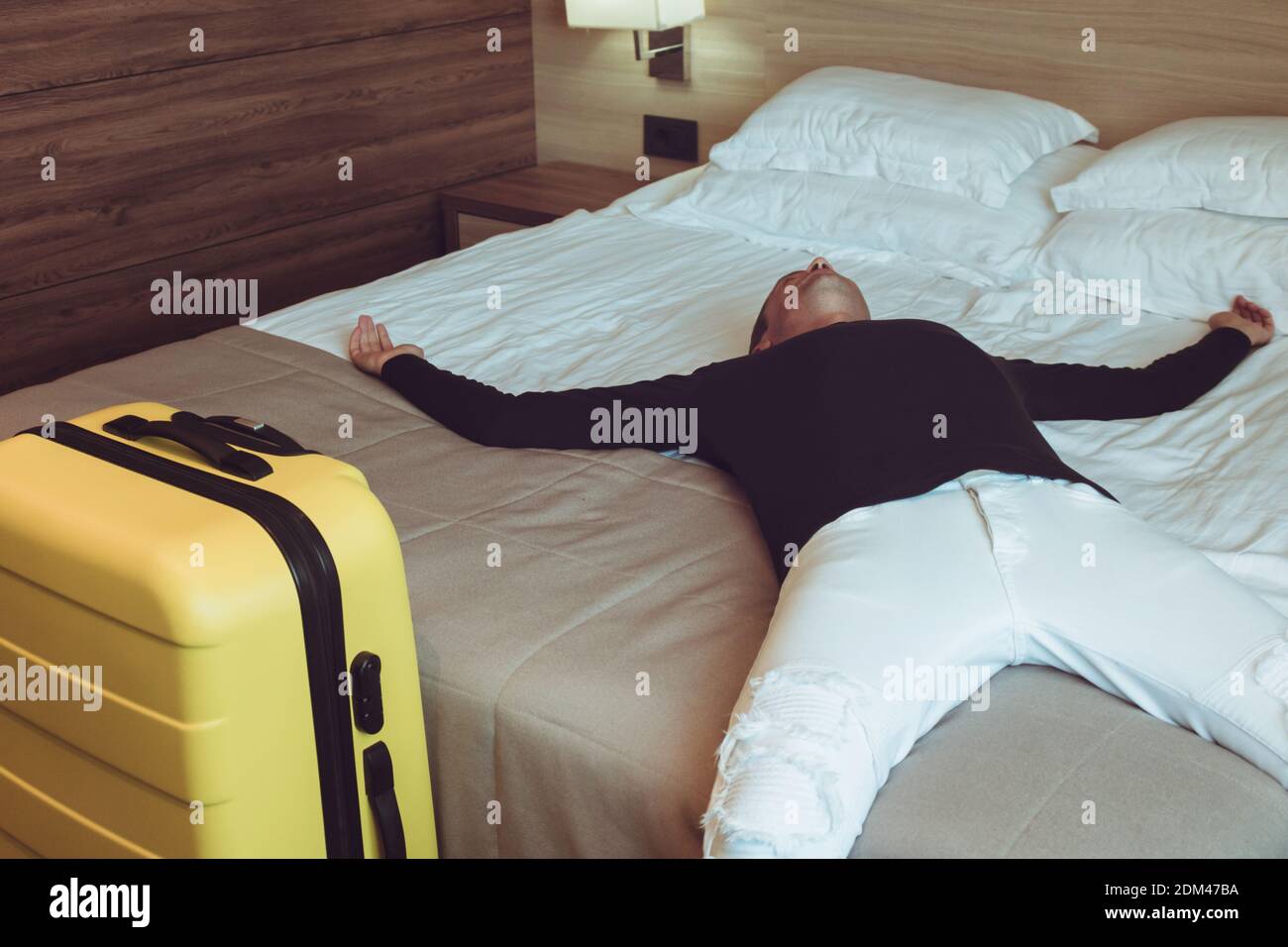 Uomo sdraiato sul letto nella camera dell'hotel Foto stock - Alamy