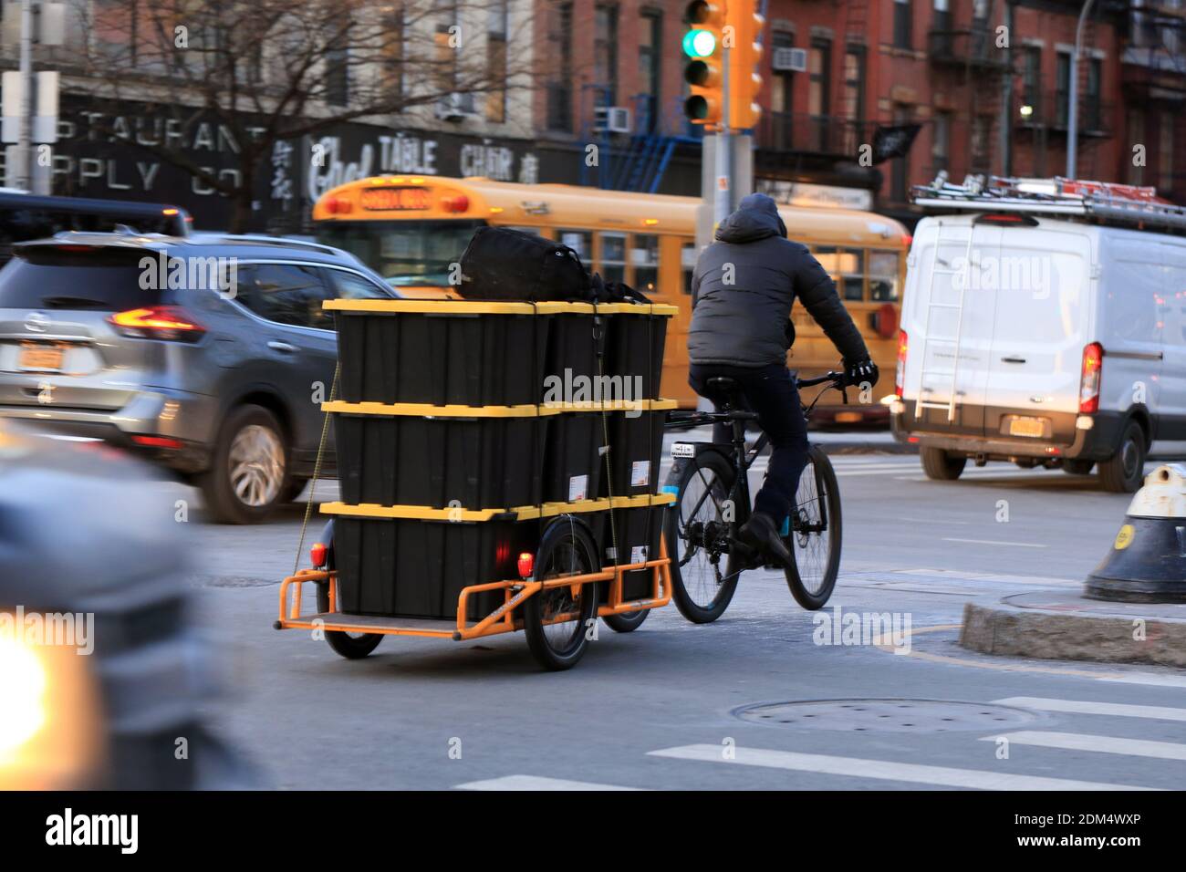 Un corriere di bicicletta su una bici di carico nel traffico pesante di New York. Foto Stock