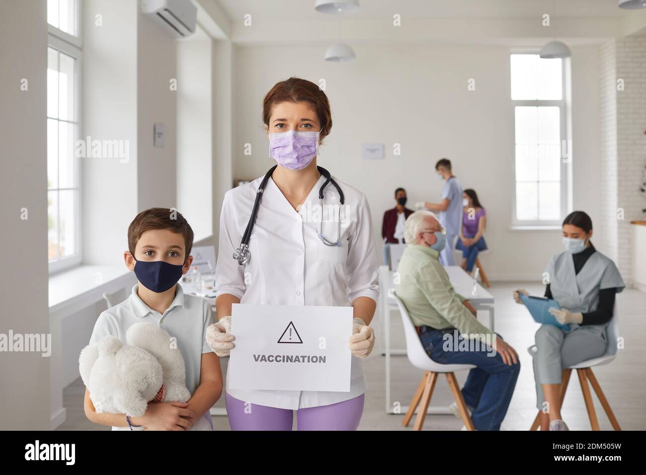 Ragazzino e medico in maschere di faccia che chiedono alla gente prendersi cura della loro salute e ottenere vaccini Foto Stock