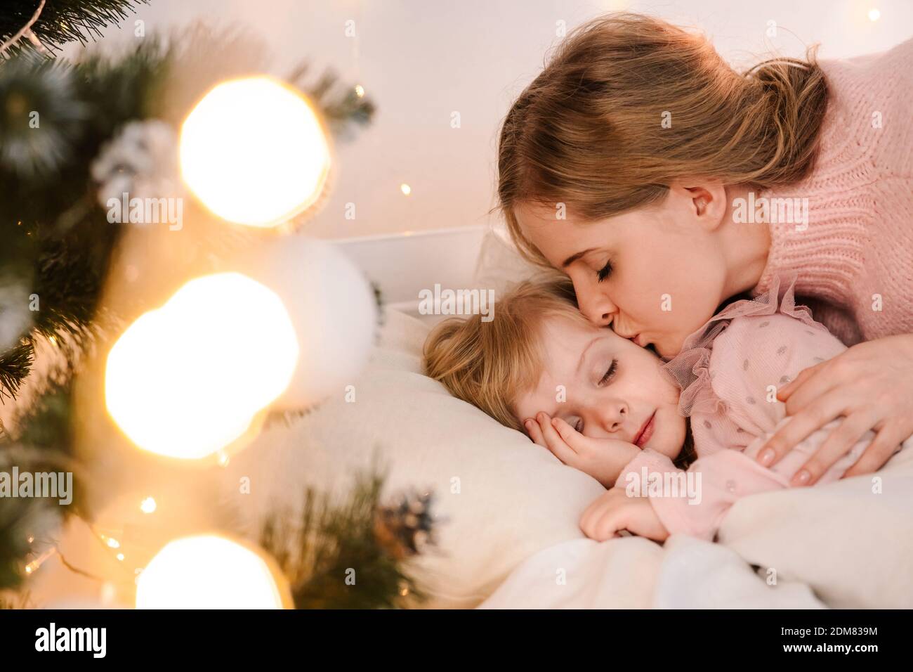 Mamma bacia addormentata figlia il giorno di natale Foto Stock