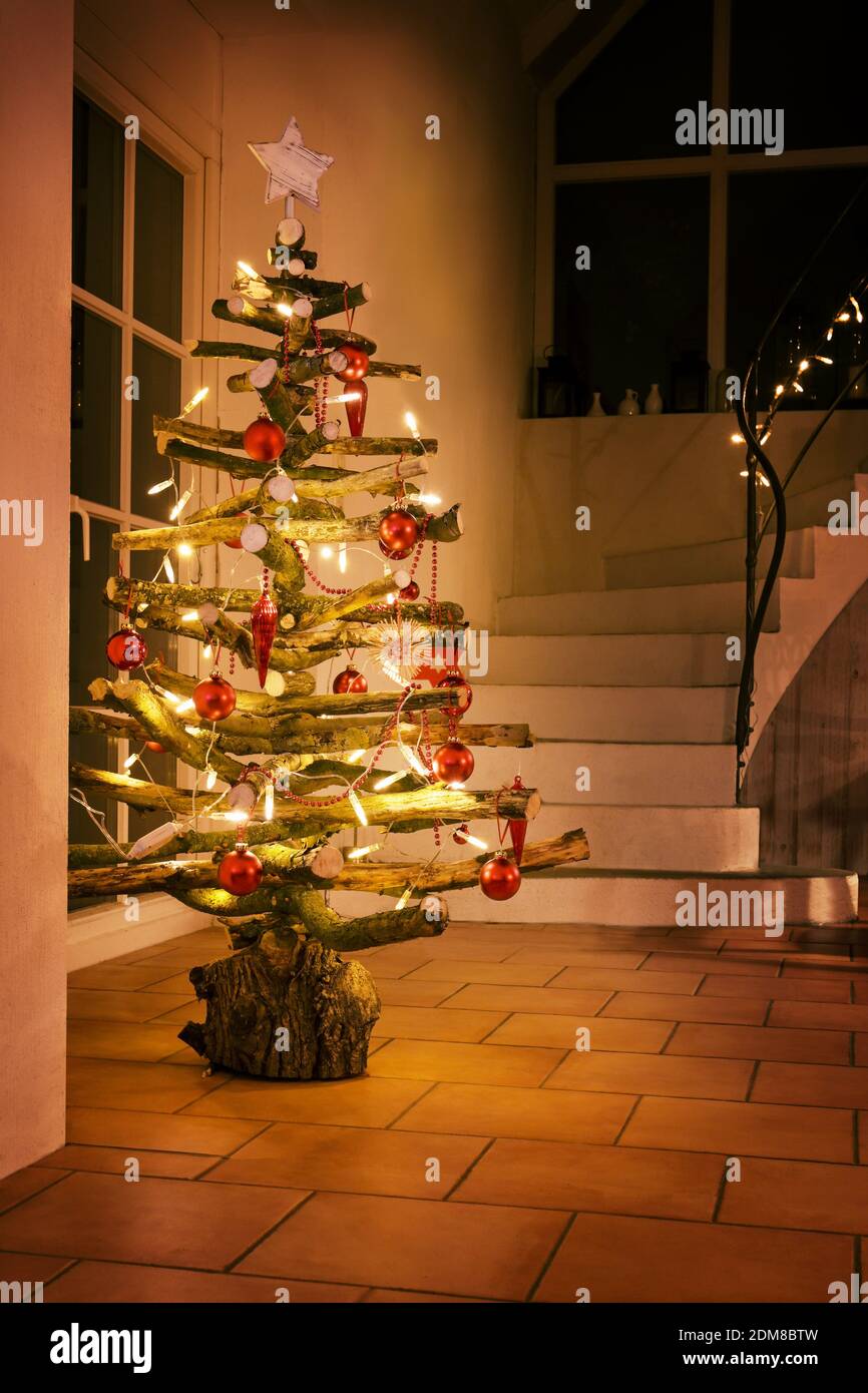 Albero di Natale rustico fatto di rami di legno grezzo decorato con luci  fiabe incandescenti e palline rosse in una scala di notte, fuoco  selezionato, dept stretto Foto stock - Alamy