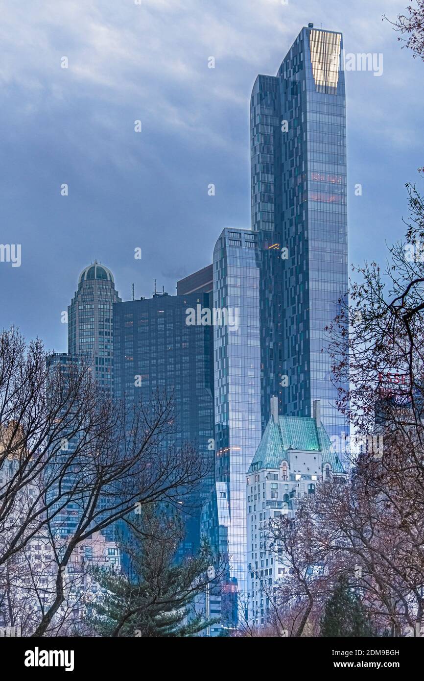 Vista degli edifici alti e moderni di Central Park South dall'interno di Central Park in autunno con fogliame in primo piano e cielo di luna sullo sfondo. Foto Stock