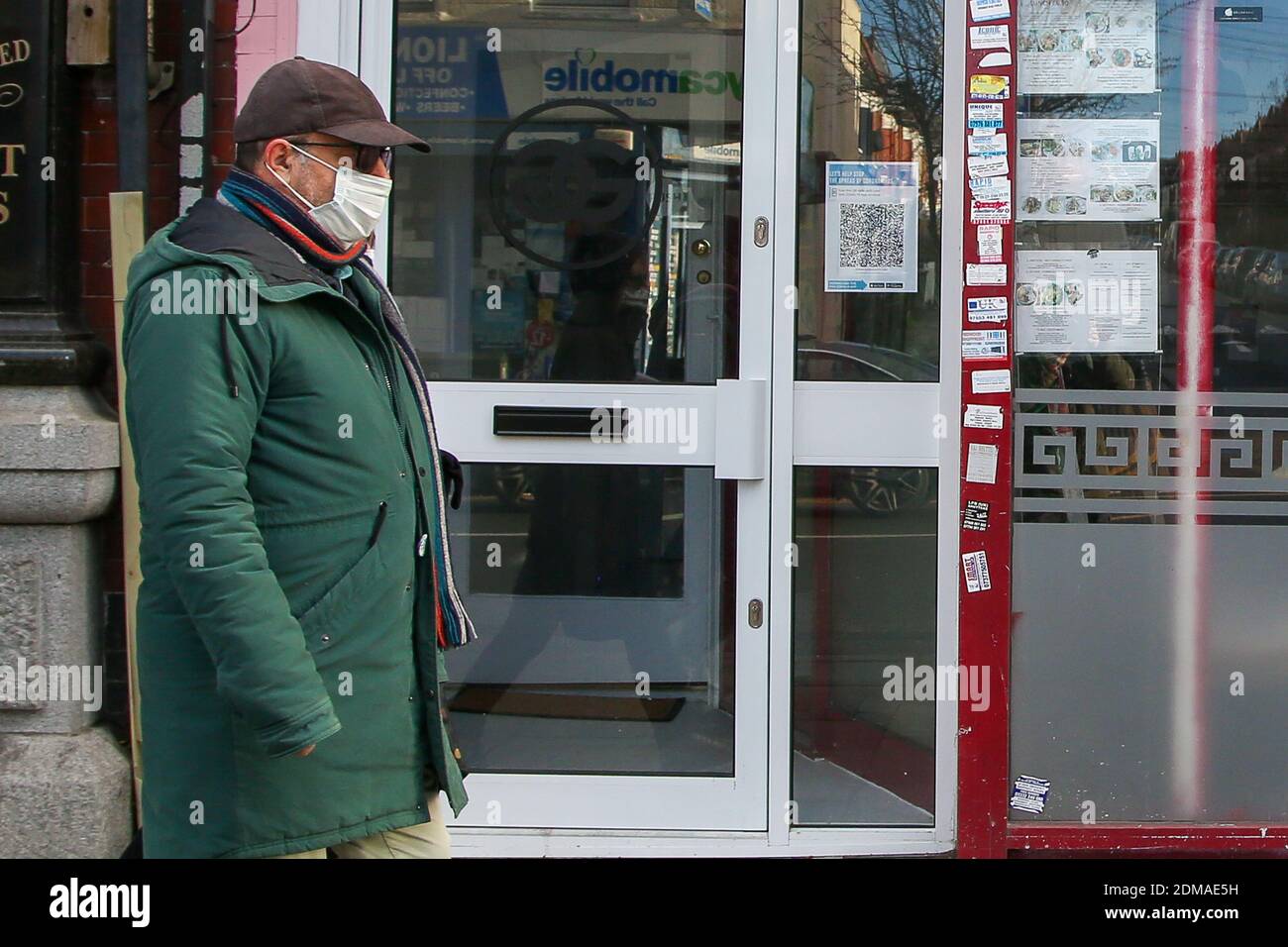 Un uomo che indossa una maschera facciale cammina per strada a Londra mentre si sposta in tre livelli COVID-19 restrizioni. Secondo gli scienziati, indossare una maschera facciale quando all'esterno può rallentare la diffusione del coronavirus. Foto Stock