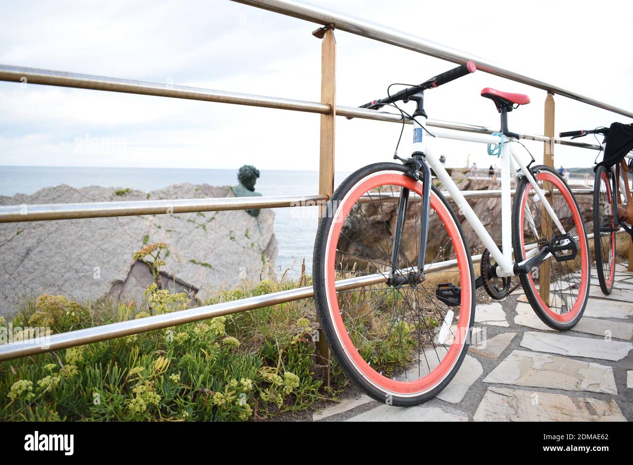 bicicleta blanca paracadas una barandilla blanca con unas maravillosas vistas al mar y al acantilado de fondo Foto Stock