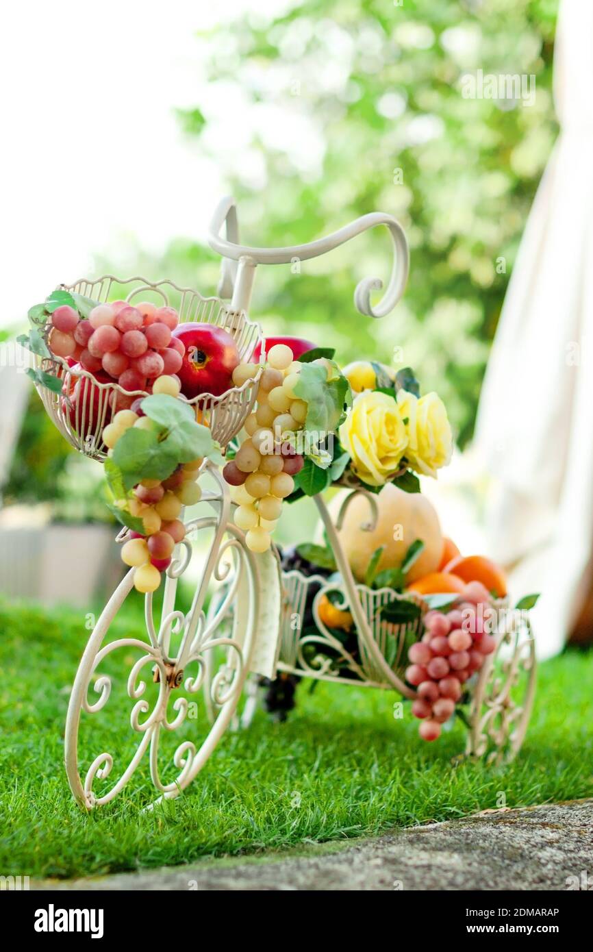 Bicicletta decorativa con frutta in cesto su sfondo verde estivo. Foto Stock