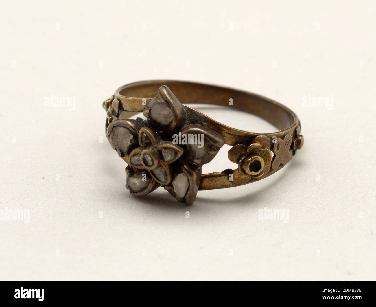 Anello, oro, diamanti rosa, anello d'oro che si separa in due fasce su cui  è un ornamento di un fiore (fatto di oro) con petali di diamanti rosa. Ai  lati dell'anello vi