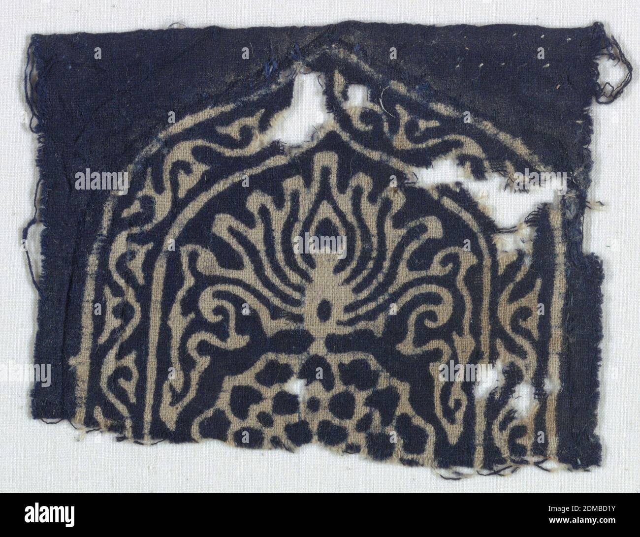 Fragment, Medium: Cotone tecnica: Resist-stampato su tessitura piana, il Design è stampato a resistenza in indaco, riservato in colore naturale; mostra la metà superiore di una forma a scudo con bordo che racchiude arabeschi o viti. Un loto stilizzato si trova all'interno dello "sheld" e, al di sotto, è visibile la metà di una forma a petalo circolare. La stampa inversa è identica e altrettanto chiara, India, XIV-XV secolo, tessuti stampati, tinti e dipinti, frammenti Foto Stock