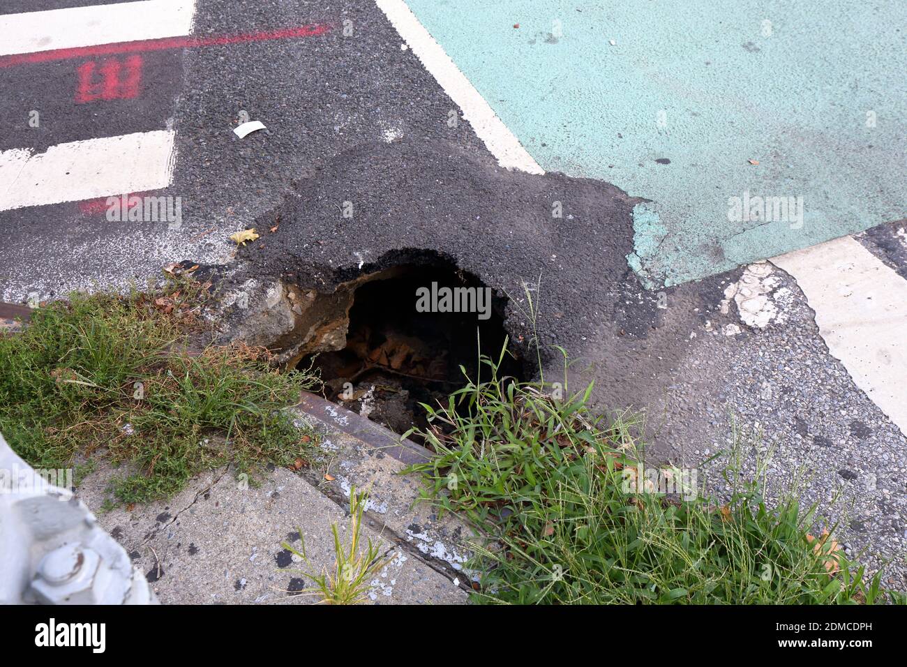 Una piccola sinkhole e una precedente area asfaltata di quella buca del lavandino in una crosswalk di New York City. Agosto 23, 2020. Foto Stock