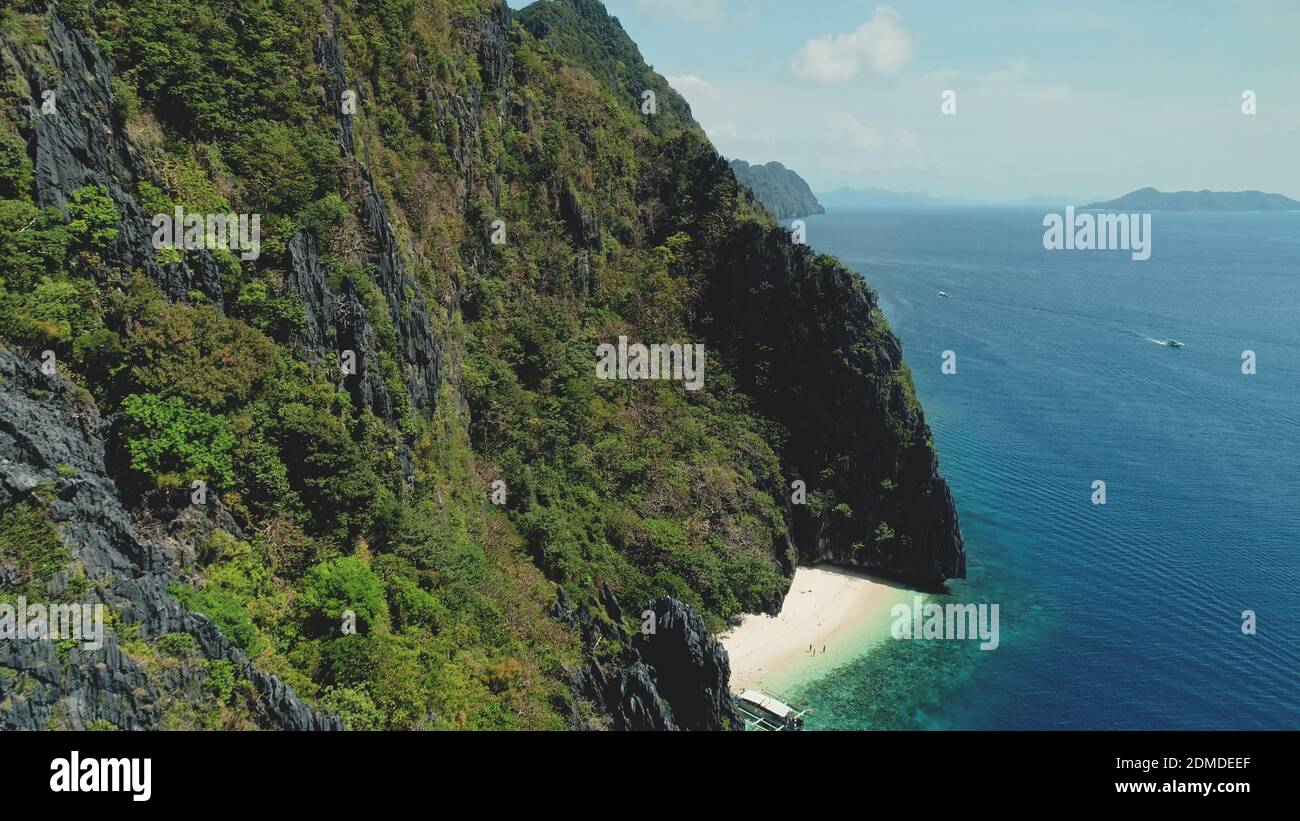 Maestoso mare di oceano baia verde spiaggia rocciosa a spiaggia di sabbia. Paesaggio dell'isola di montagna con la foresta tropicale verde della giungla. Barche a mare lungomare di Palawan Island, Filippine, Asia drone colpo Foto Stock