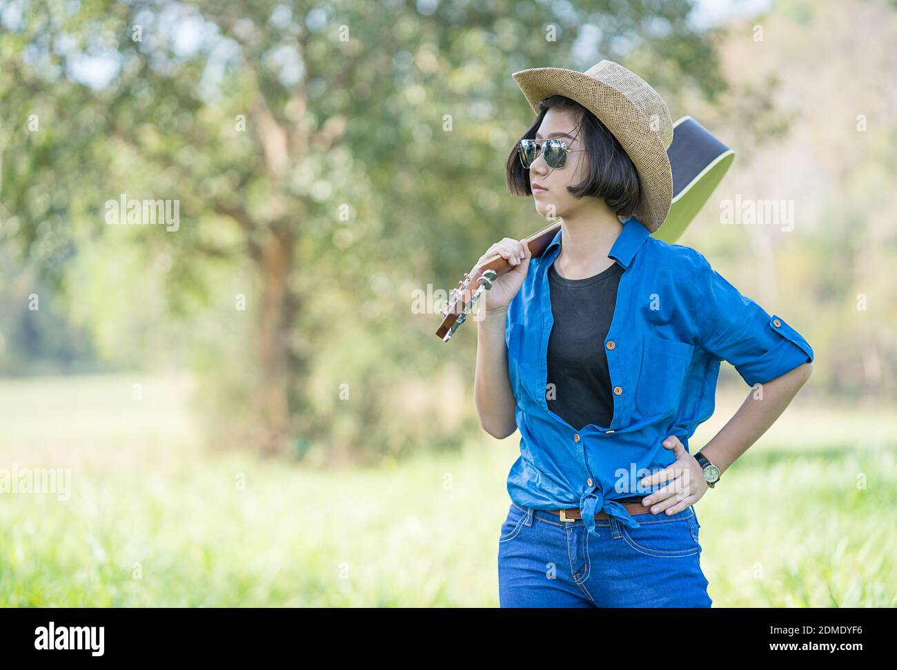 Giovane donna asiatica di capelli corti indossare un cappello e portare la  sua chitarra in erba campagna sul campo della Thailandia Foto stock - Alamy