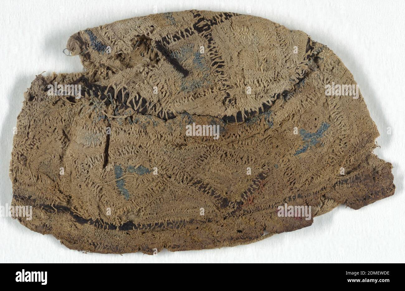 Cappello, Medio: lino, seta, lana tecnica: Tessitura liscia ricamata e trapuntata, testa di teschio con corona circolare piatta, fascia attorno alla testa, di doppio spessore di lino non tessuto con decorazione ricamata, trapuntata e coulita. Diamanti intorno alla fascia con varie otturazioni in forma di punto a spina di pesce; doppie strisce di protezione in alto e in basso che racchiudono quelle che possono essere iscrizioni islamiche. Corona divisa in quattro quadrati irregolari contenenti motivi illeggibili in forma di osso arricolare. In lino naturale e blu, filo di seta rosa, blu e giallo; grappoli spessi di filo di seta nero catturati dal lino Foto Stock