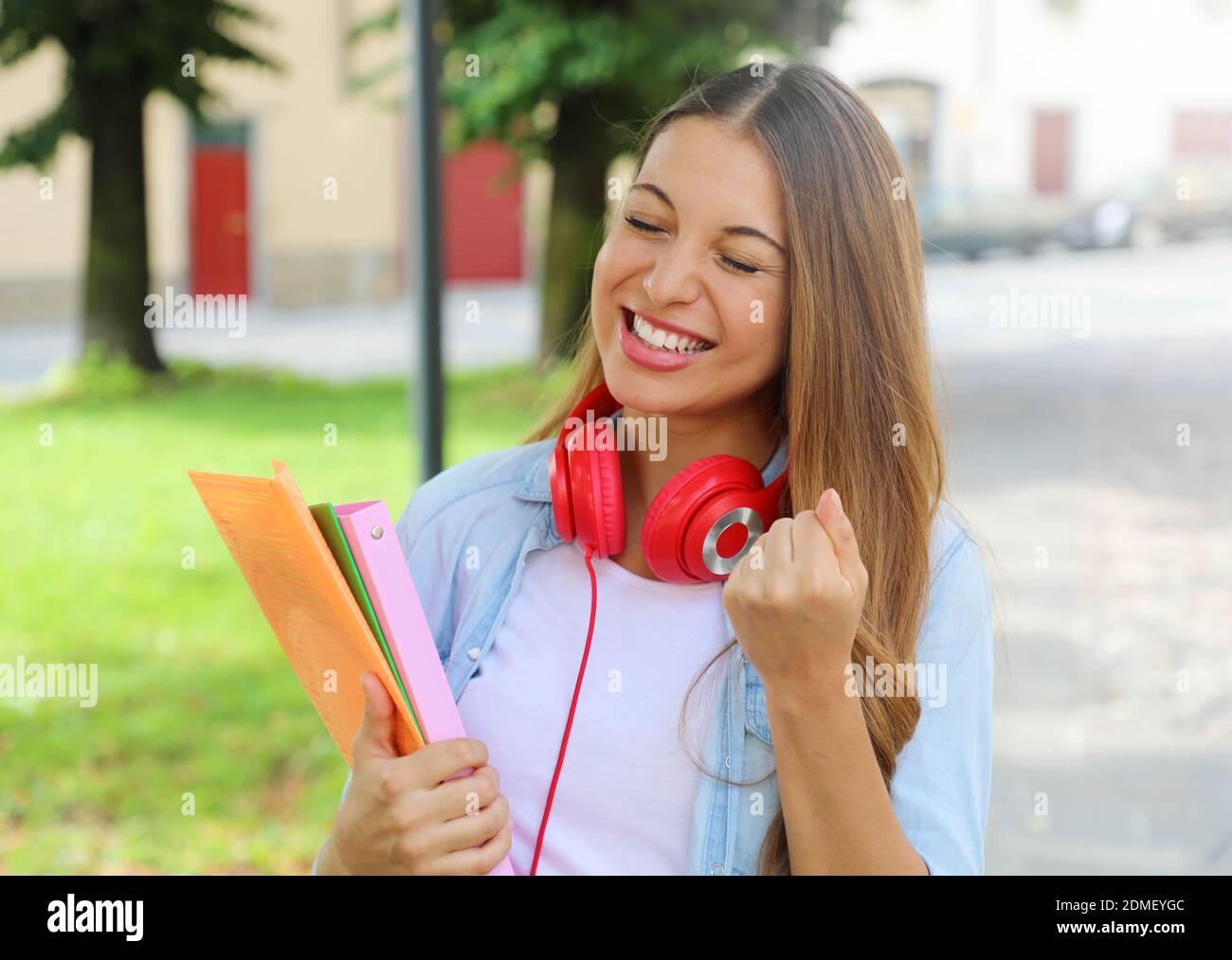 Ritratto di entusiasti ridere ragazza adolescente con braccio di sollevamento celebrando all'esterno. Foto Stock