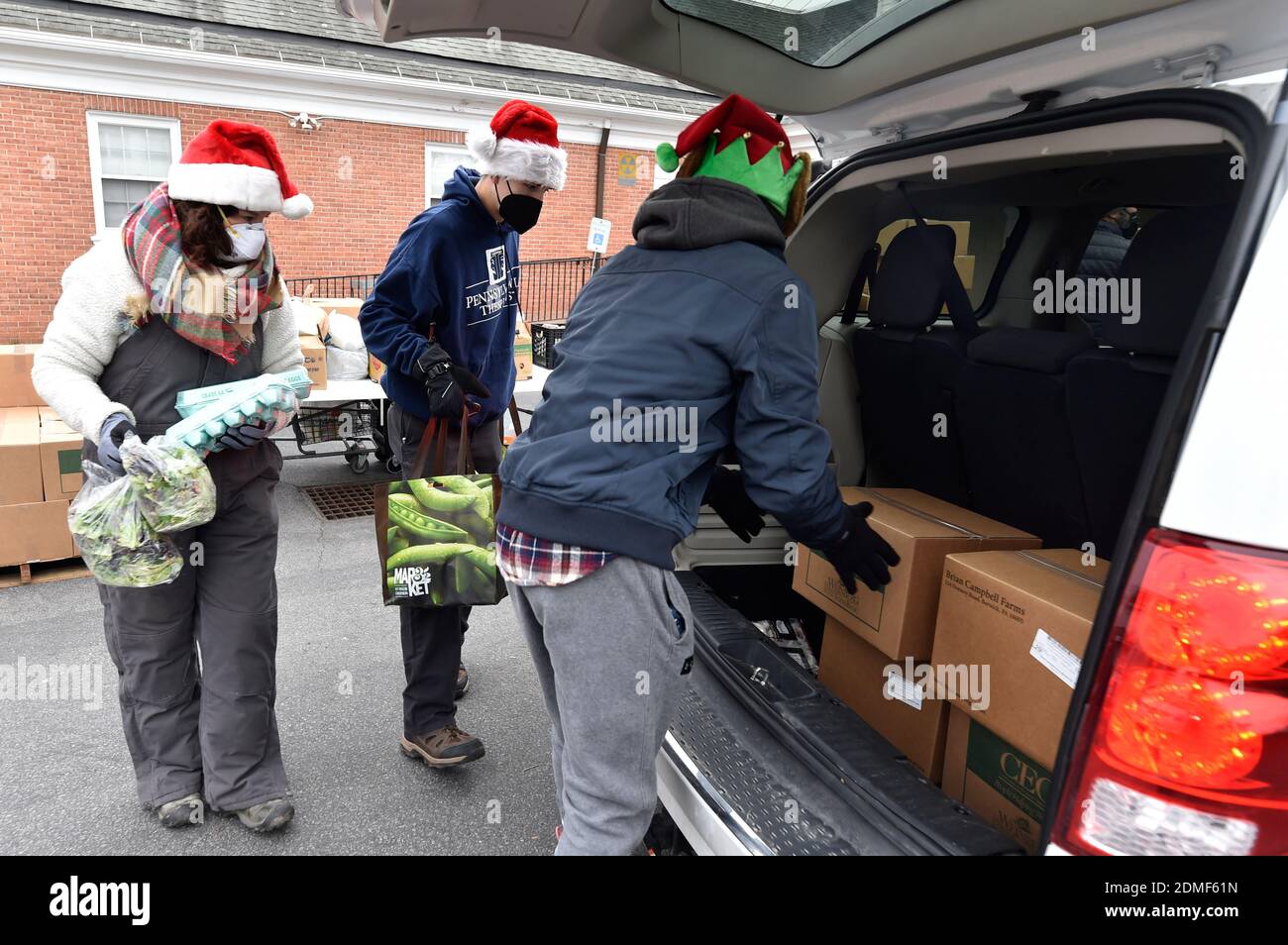 Kingston, Stati Uniti. 16 Dic 2020. I volontari hanno messo il cibo nel bagagliaio di un veicolo ad un azionamento senza tocco attraverso la dispensa del cibo.Sin dall'inizio di Covid la dispensa del cibo di al Beech è stata molto occupata, oggi hanno servito là un millionesimo ospite. Per i volontari di Natale indossavano cappelli Santa e consegnavano carte regalo, caramelle e palloncini insieme ai normali prodotti alimentari. Credit: SOPA Images Limited/Alamy Live News Foto Stock