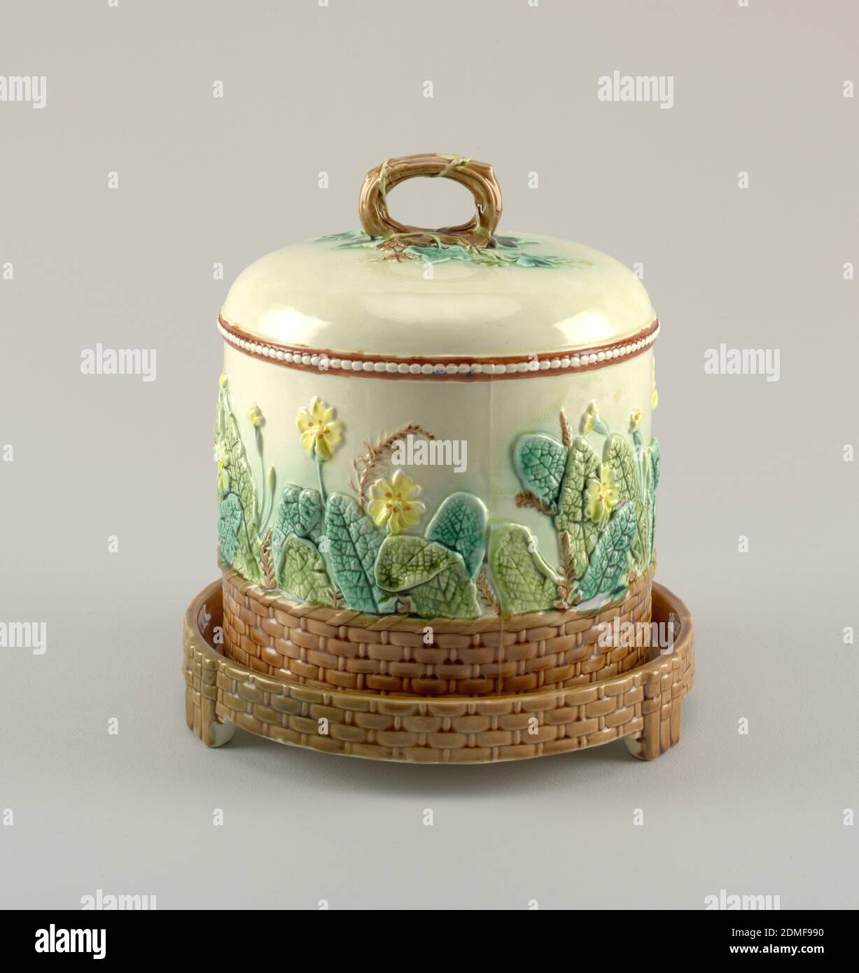 Piatto e coperchio, Wedgwood, inglese, stabilito 1759, terracotta smaltata, A) campana cava cilindrica, a faccia dritta, piatto superiore. Modellato con rami di prunus a fiore asimmetrico in marrone con fiori rossi, foglie verdi e marroni, e con grappoli di crisantemi. La parte superiore della campana contiene un ornamento simile, con impugnatura a spirale applicata. B) piatto adattato per ospitare la copertura, su tre piedi, decorato al confine con rami prunus e fiori., Inghilterra, ca. 1880, ceramica, arti decorative, piatto e copertina Foto Stock