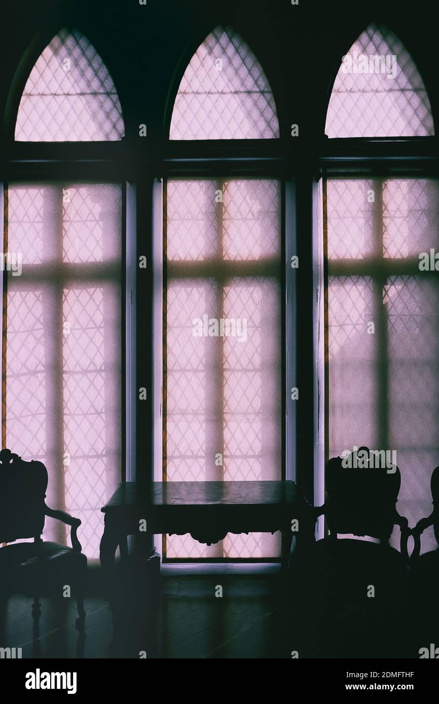 sedia e tavolo in luce scura contro una finestra Foto Stock