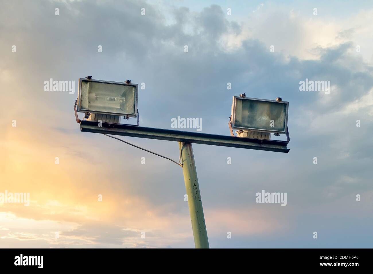 Set di due proiettori all'aperto e un palo per lo stadio sportivo, parcheggio auto o illuminazione di un parco pubblico contro il bellissimo cielo tramonto e nuvole backgr Foto Stock