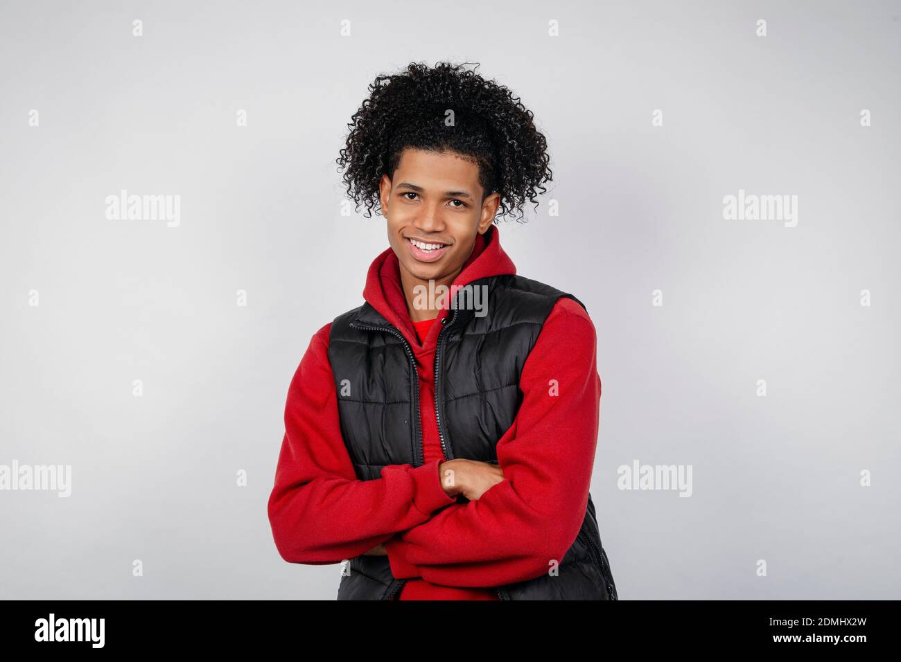 Un giovane afro-americano sorridente casual che si posa isolato su uno sfondo bianco in uno studio. Concetto di stile di vita delle persone. Foto Stock