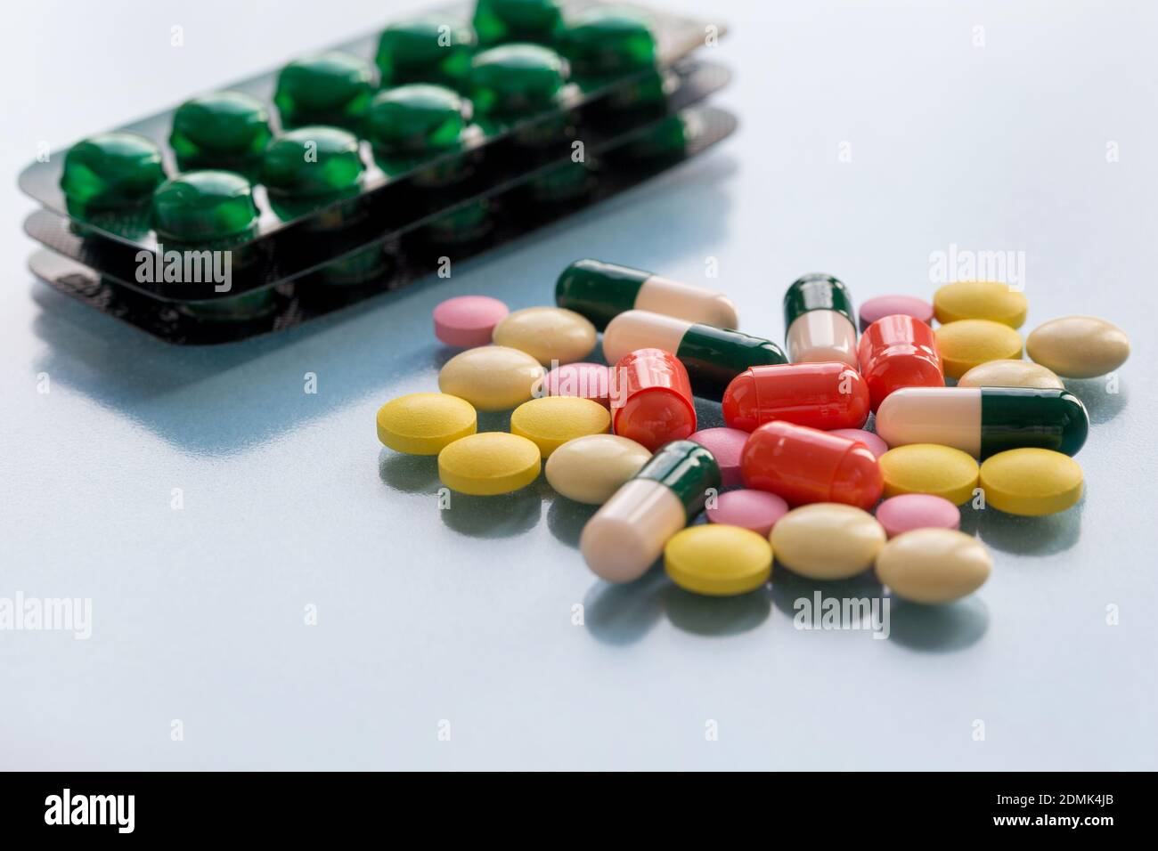 Confezioni con pillole, pillole colorate e capsule su sfondo blu. Concetto di salute medica o dipendenza da droghe. Foto Stock