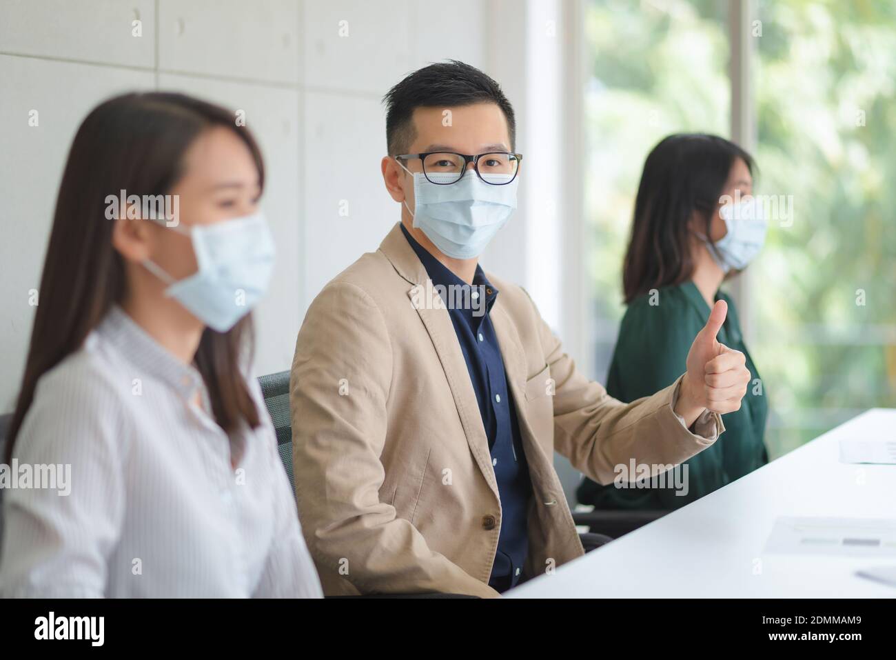 I dipendenti aziendali che indossano la maschera durante il lavoro in ufficio da tenere Igiene seguire Company policy.Preventive durante il periodo di epidemia da coronavirus Foto Stock