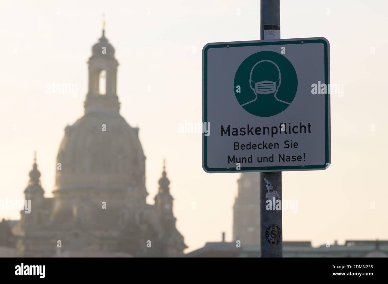 Dresda, Germania. 17 Dicembre 2020. Un cartello che indica che le maschere sono obbligatorie è appeso su un lampione di fronte alla Frauenkirche. In Sassonia, tre contee hanno ora più di 600 nuove infezioni da Corona ogni 100,000 abitanti entro una settimana. Credit: Sebastian Kahnert/dpa-Zentralbild/dpa/Alamy Live News Foto Stock